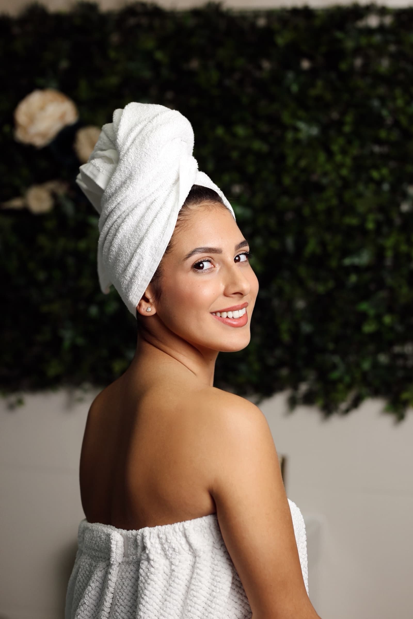 Towel turban and bare shoulders against a green hedge