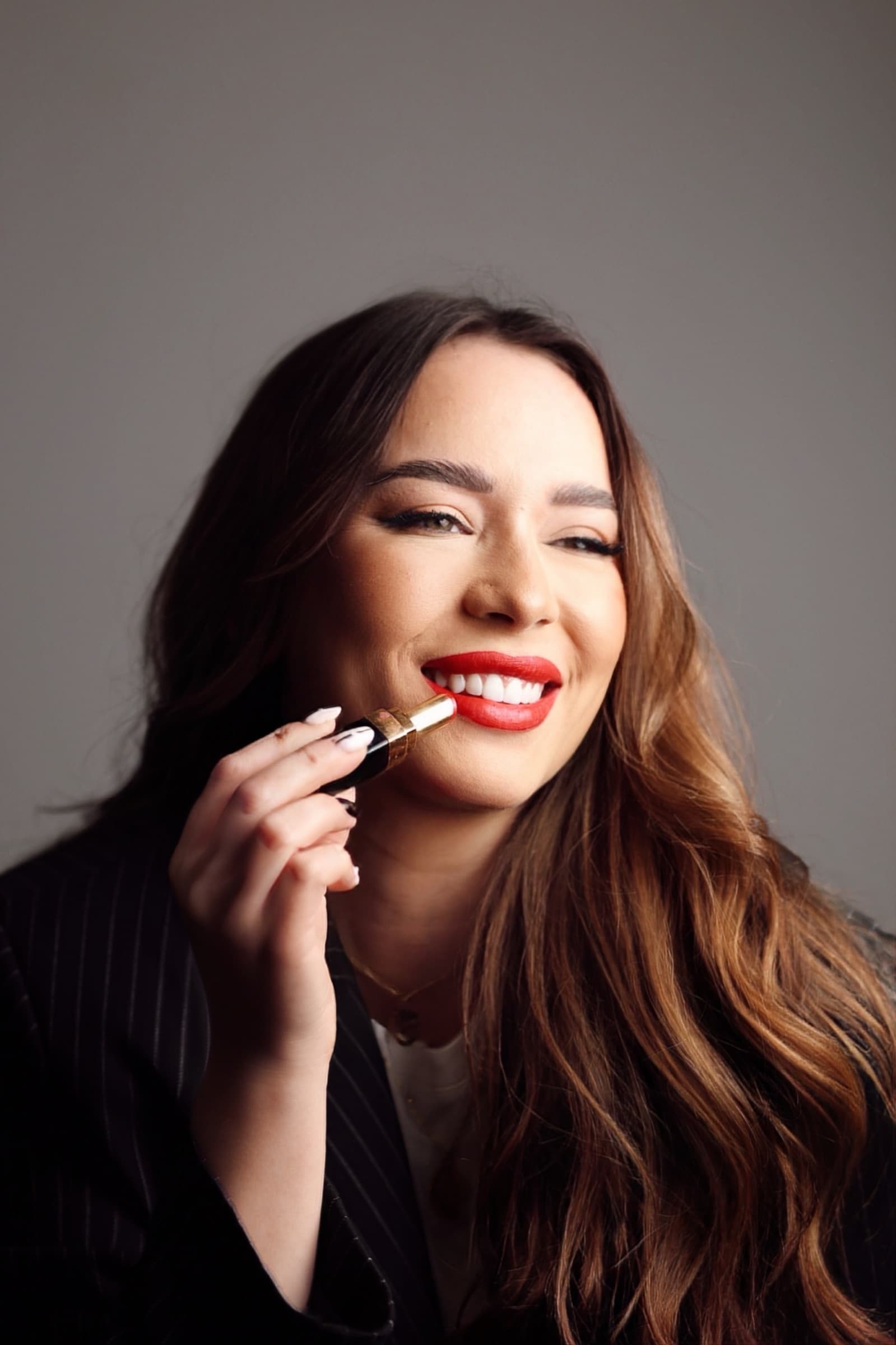 Applying a red lip, laughing into the light