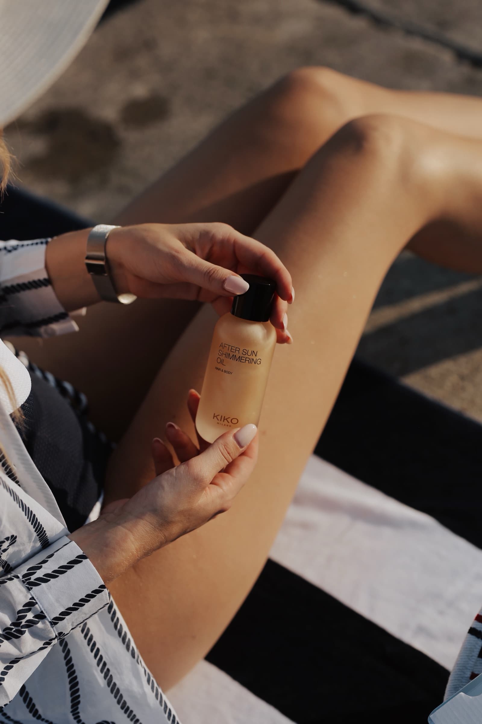 A bottle of body lotion held against sunlit legs