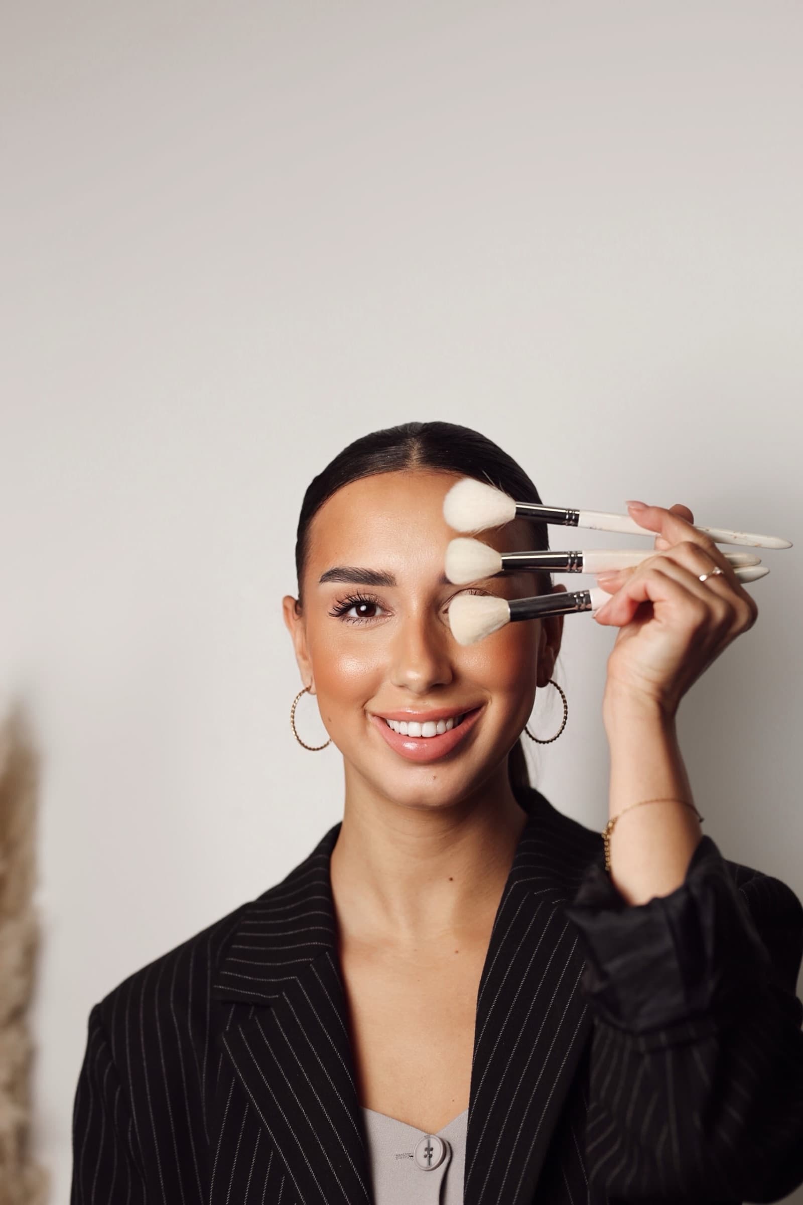 Brushes held across the face, pinstripe blazer
