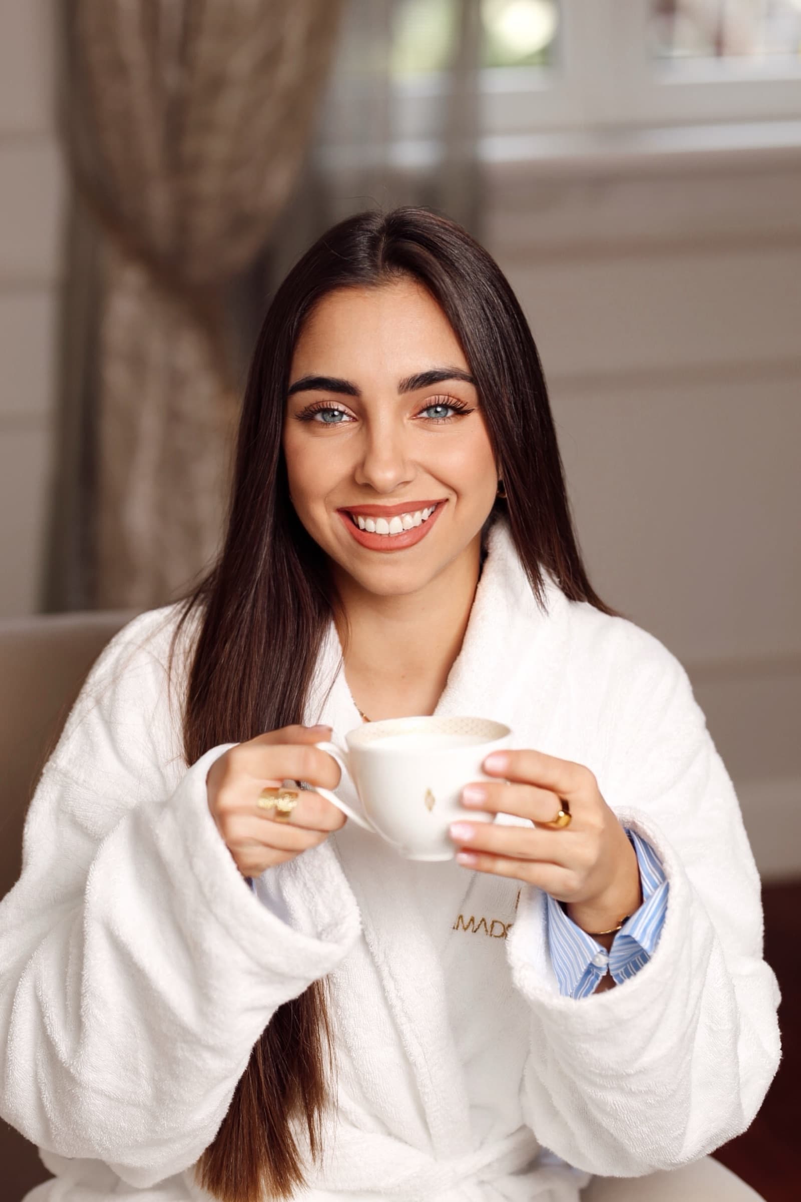 Guest in an Amadria Park robe smiling over a cappuccino
