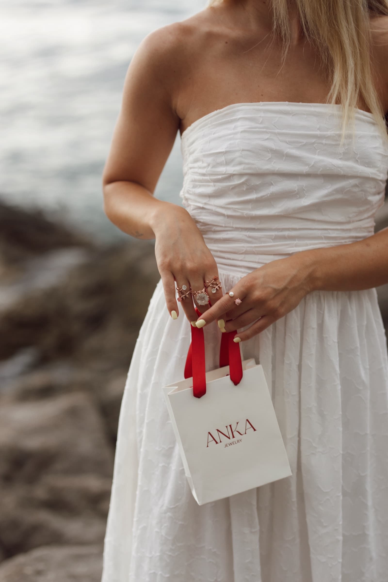 An Anka Jewelry gift bag carried in a white summer dress