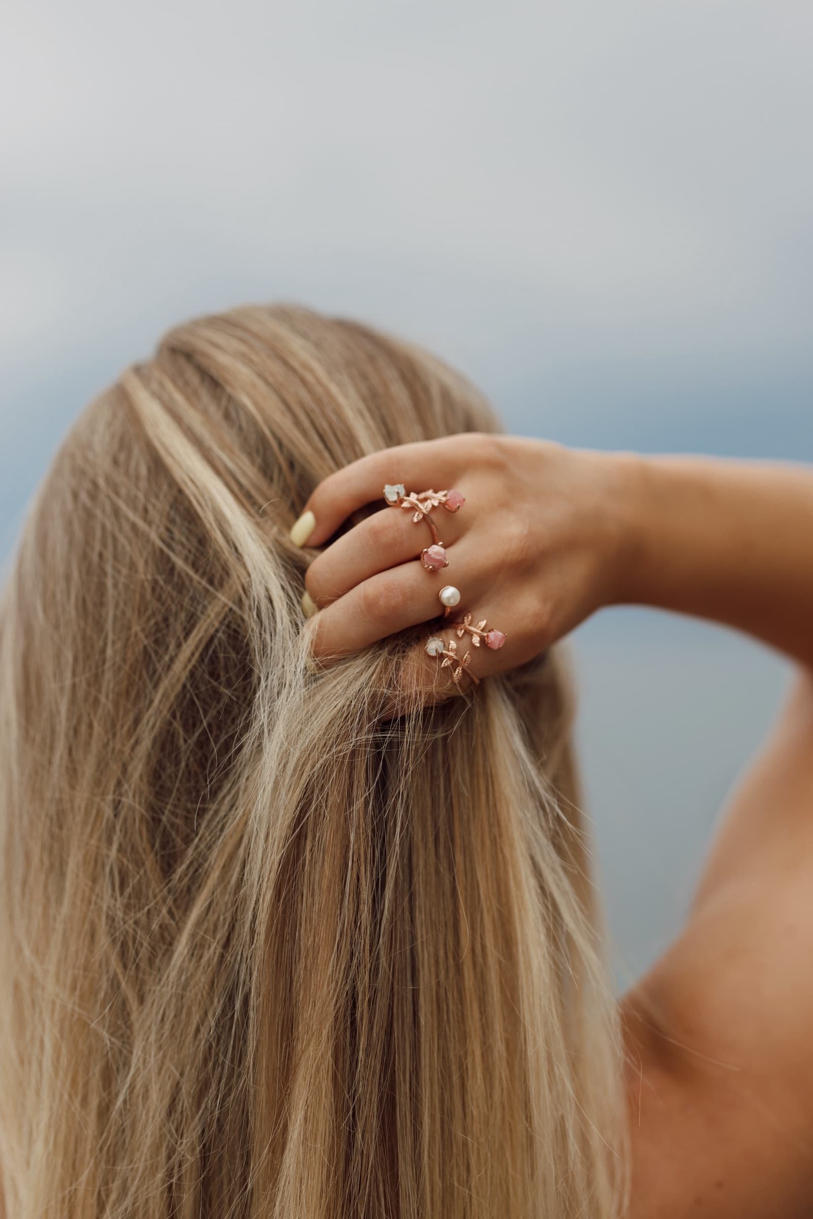 Rose gold Anka rings on a hand gathering blonde hair