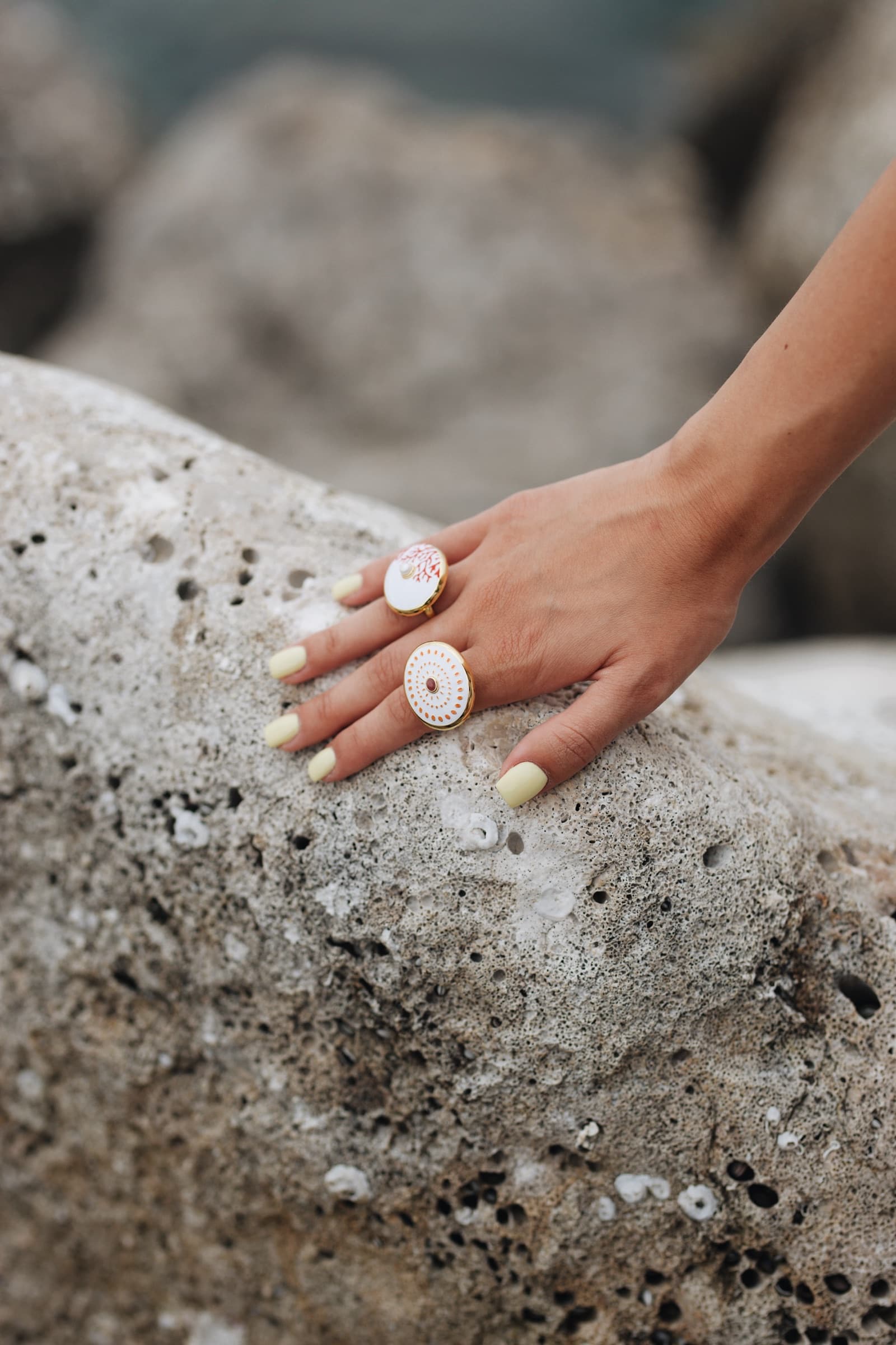 Enamel Anka rings on a hand spread across weathered stone