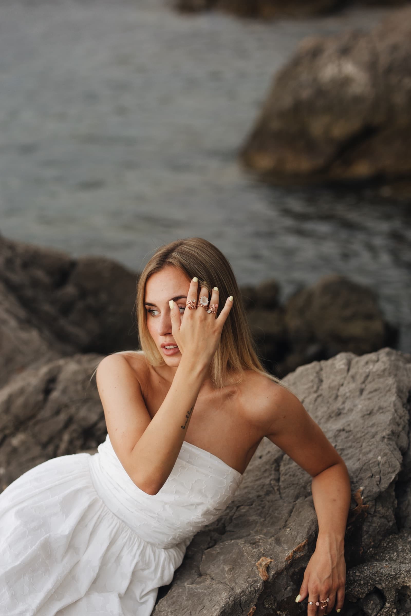 Anka rings framing the face against the rocks and sea
