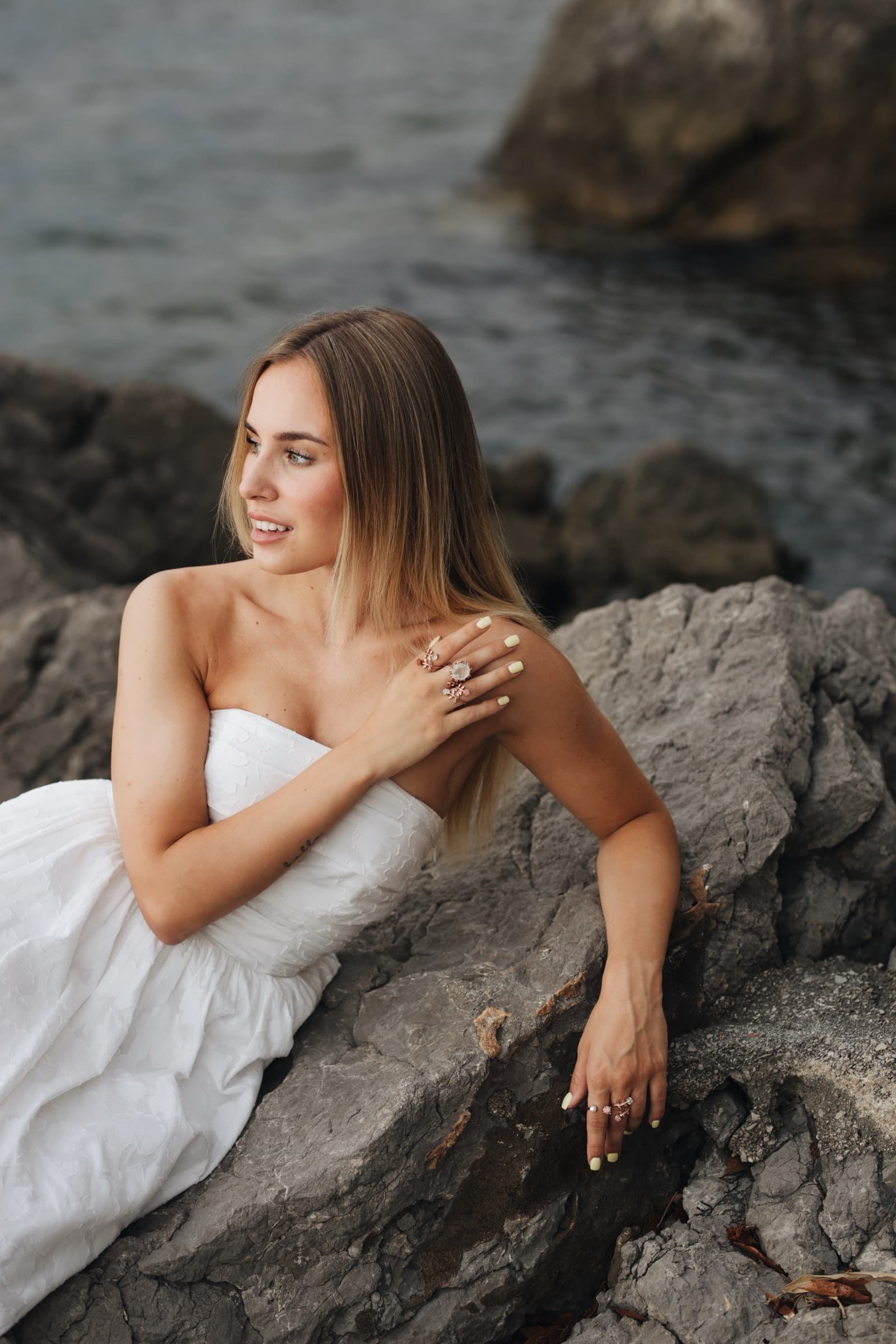 Anka rings at the shoulder, seated on rocks above the water