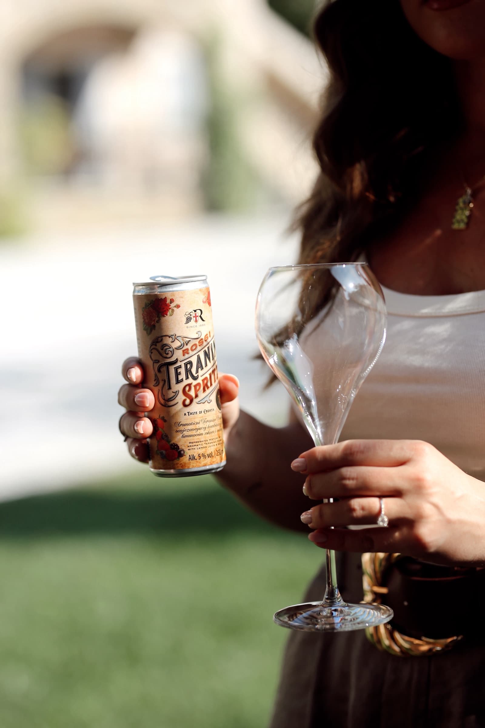Teranino Spritz can and an empty wine glass, held side by side