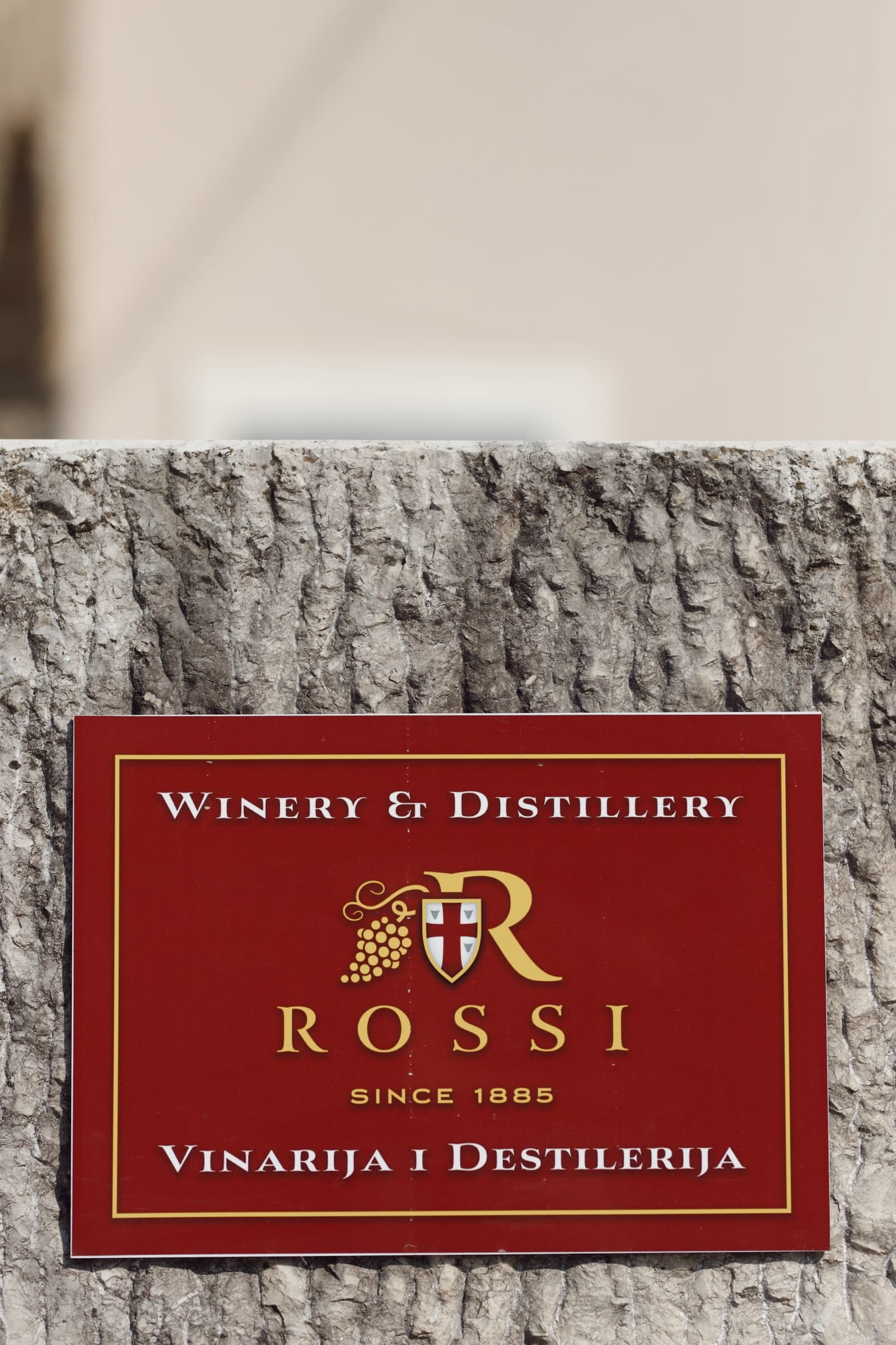 The Rossi winery and distillery sign on a cut stone wall