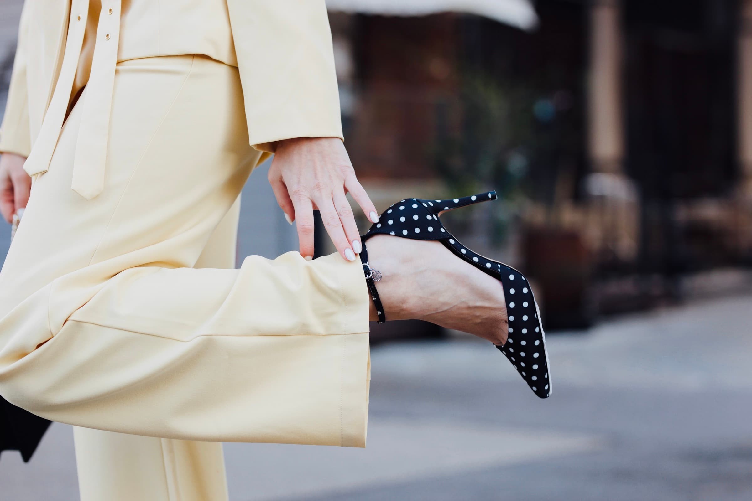 A polka-dot heel held against a cream suit