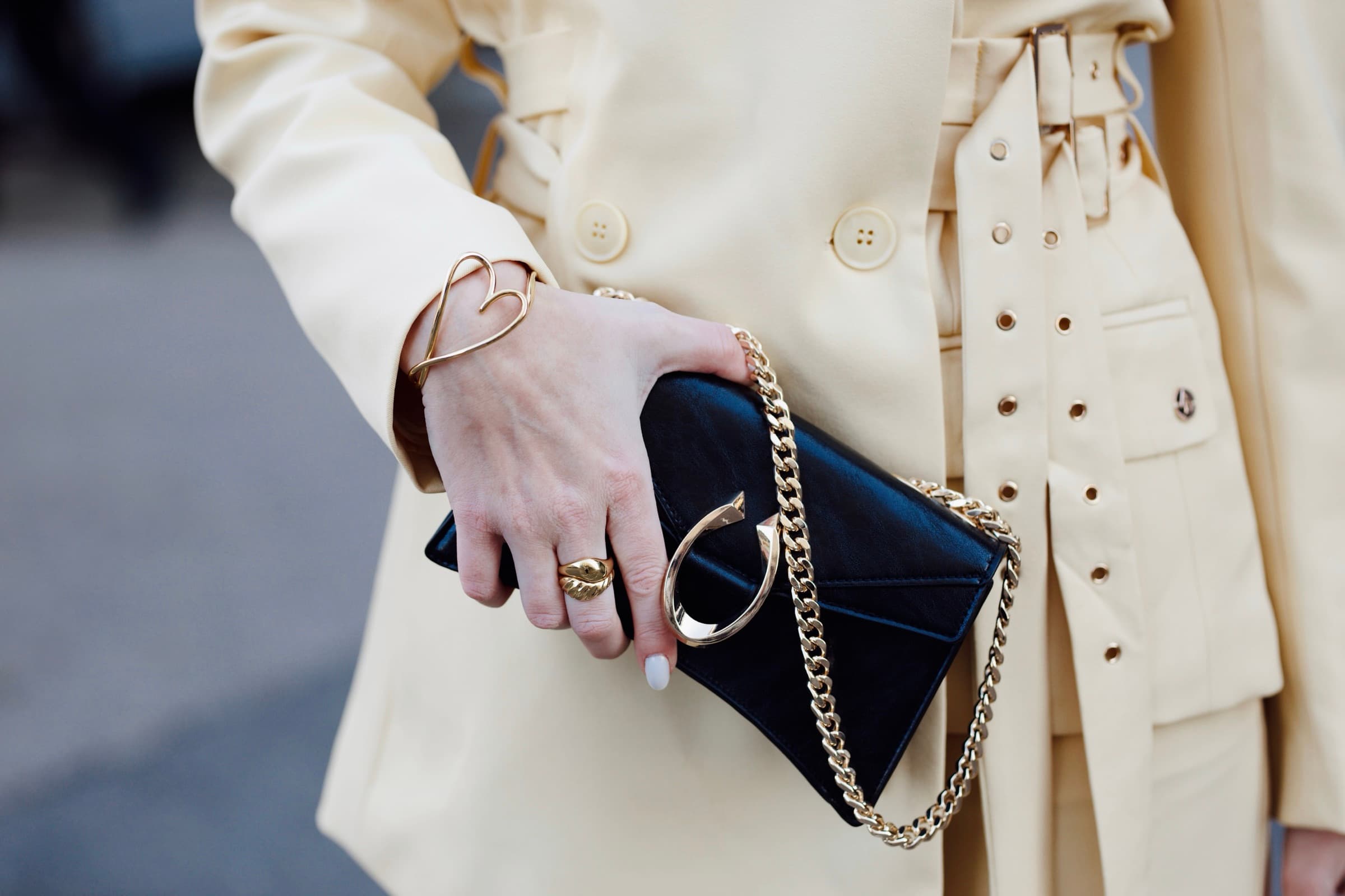 Black chain clutch against a cream trench