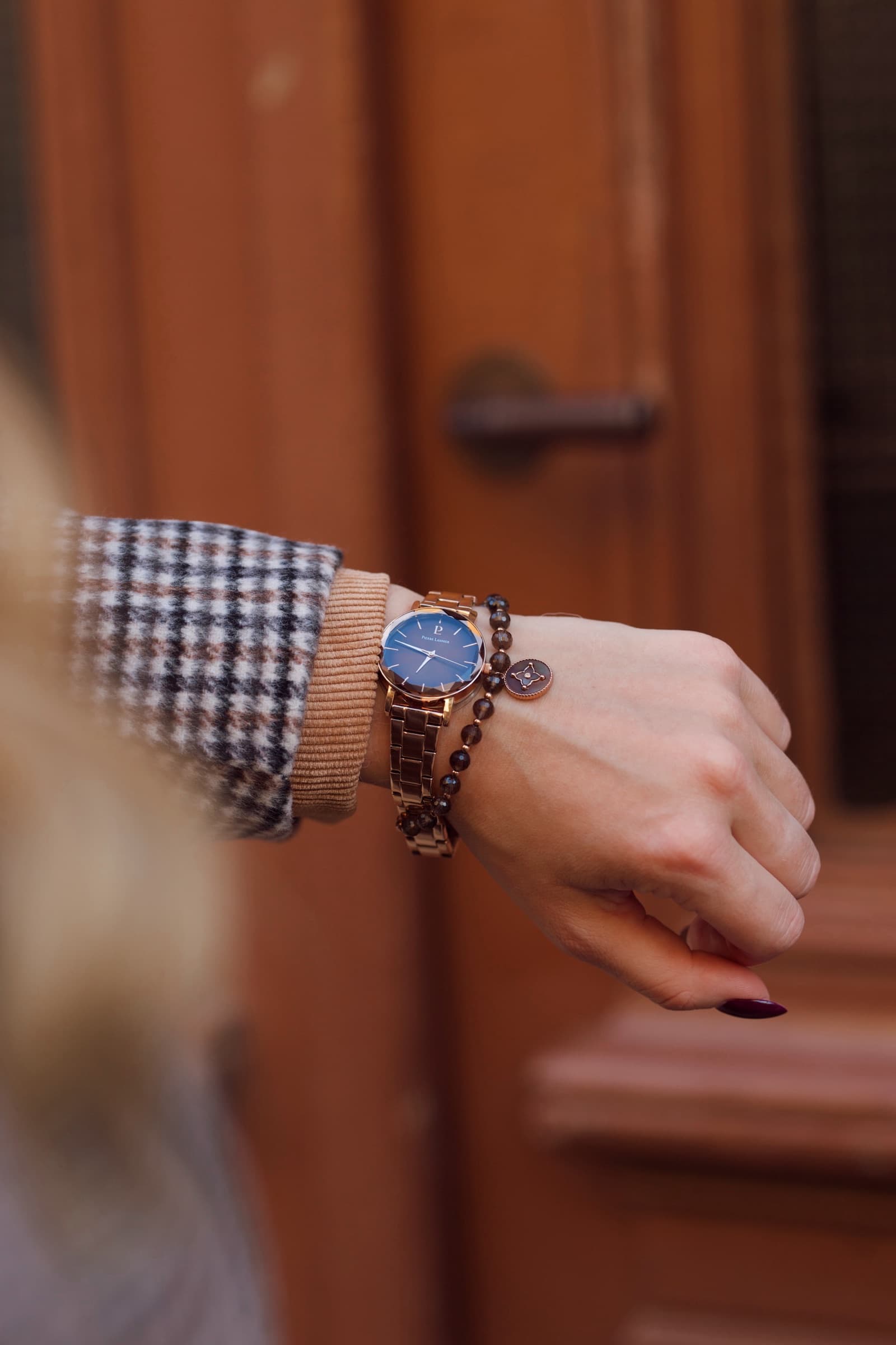 A wristwatch at the cuff of a houndstooth sleeve