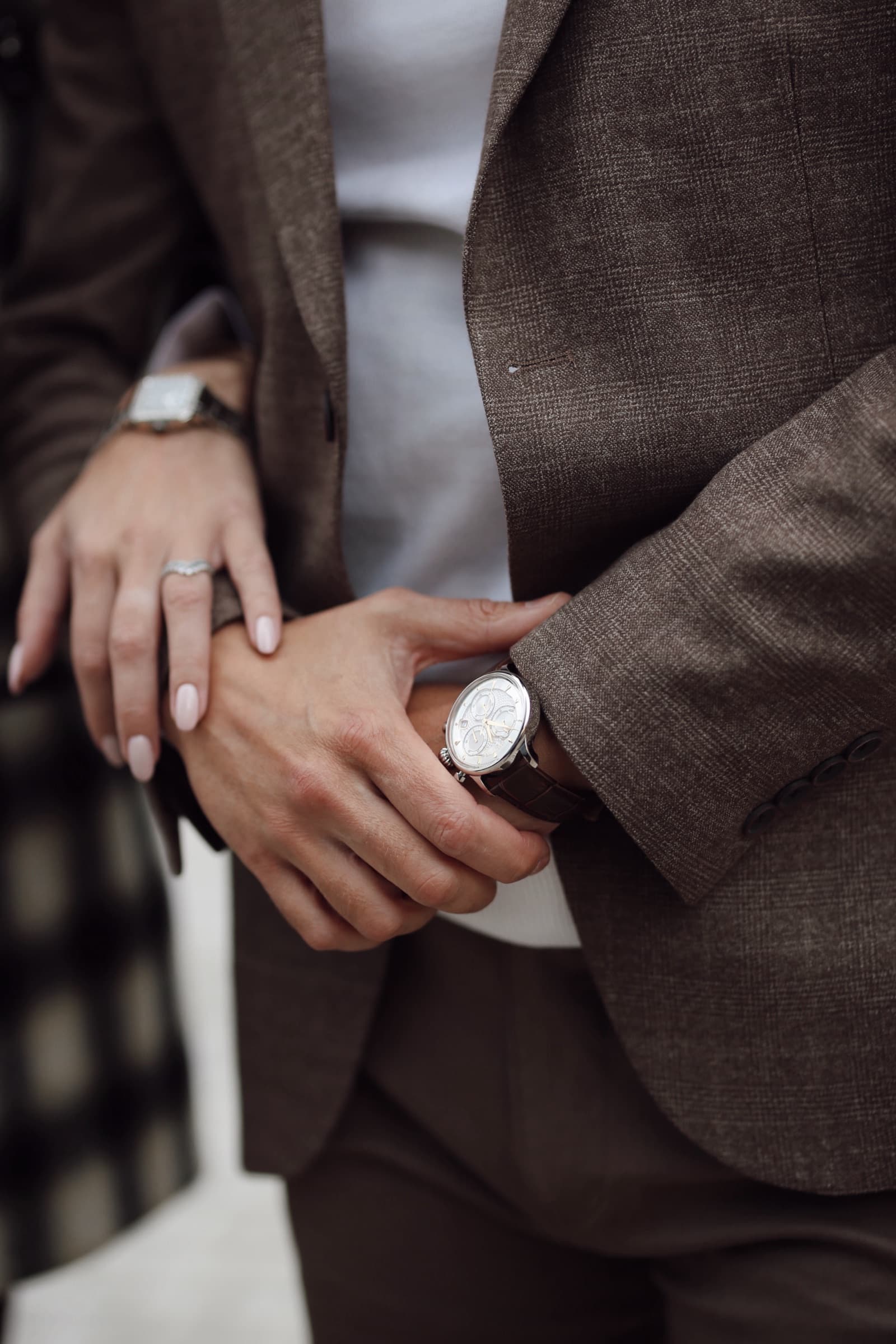 Adjusting a watch, brown suiting and a resting hand