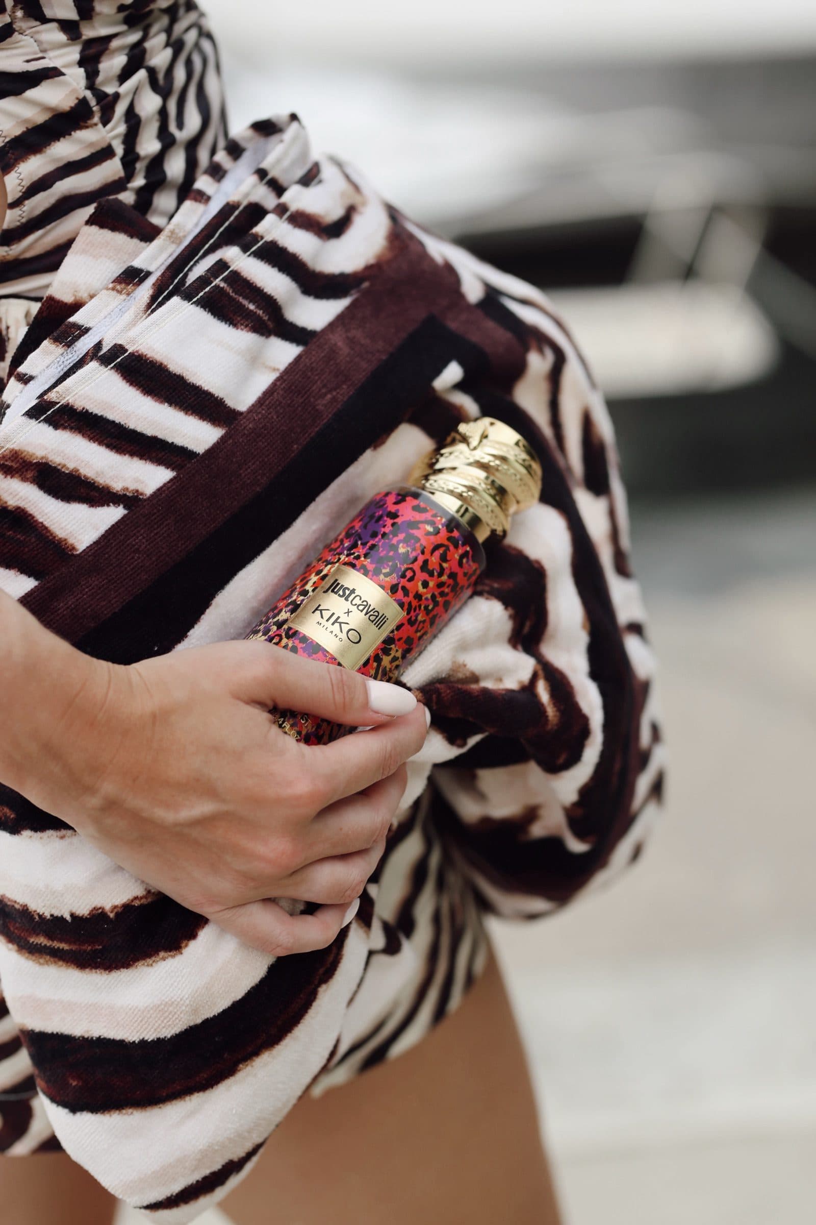 A Just Cavalli fragrance held against a rolled zebra towel