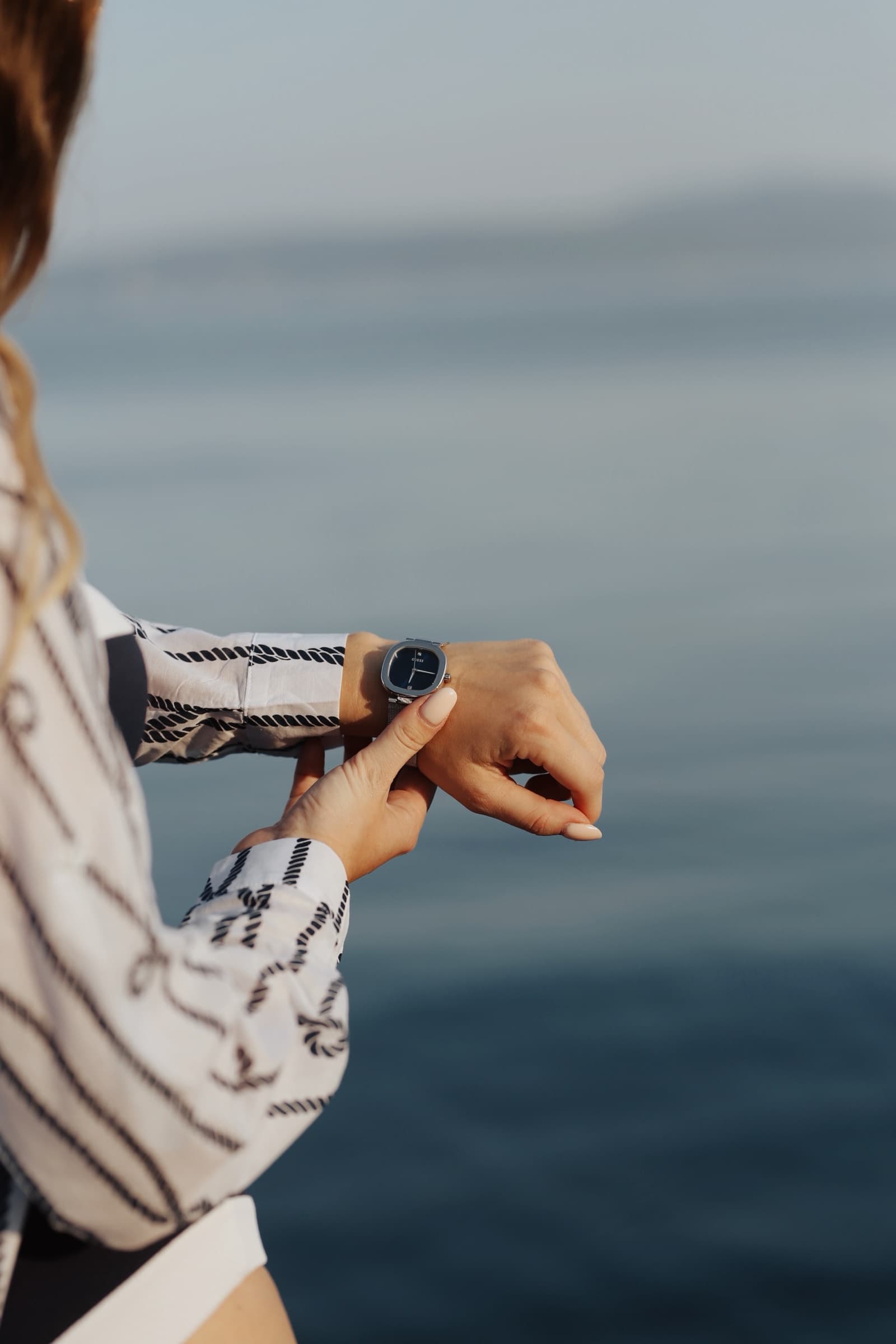 Checking a watch at the rail above the sea