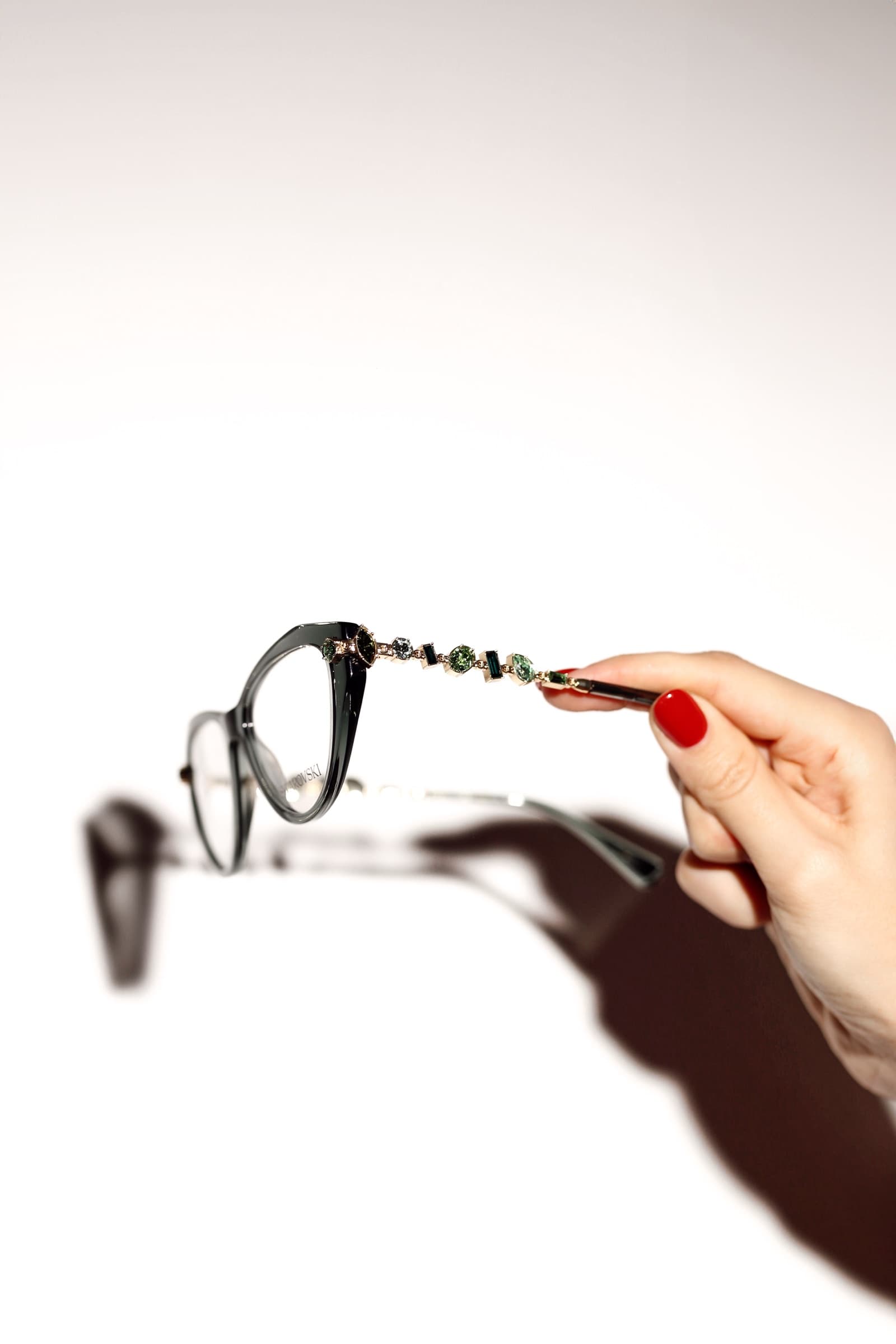 A pair of optical frames held against white, hard shadow beneath