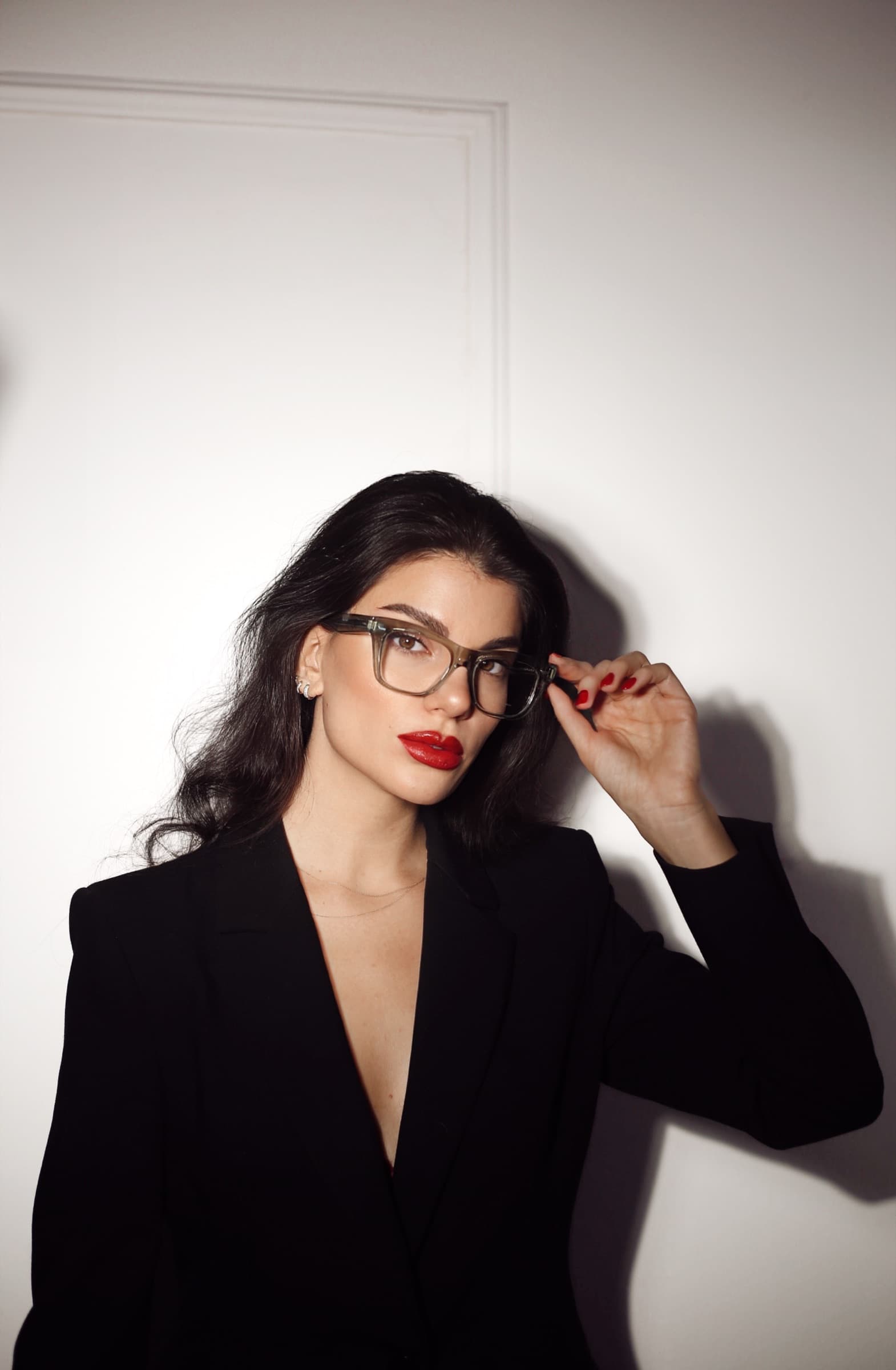 Round optical frames with a black blazer and a red lip