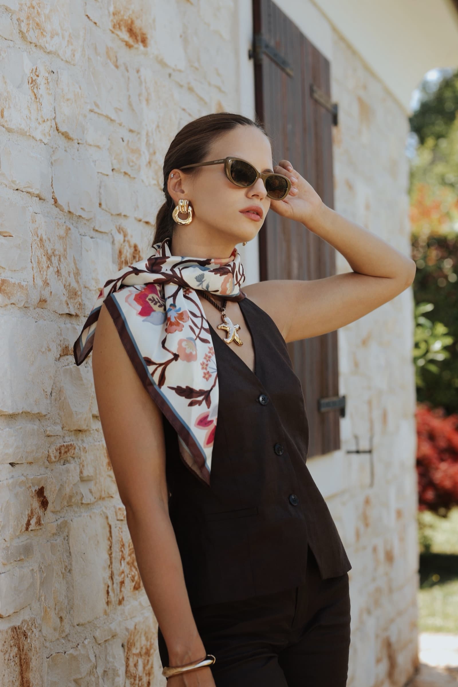 Sunglasses and a neck scarf against a whitewashed stone wall