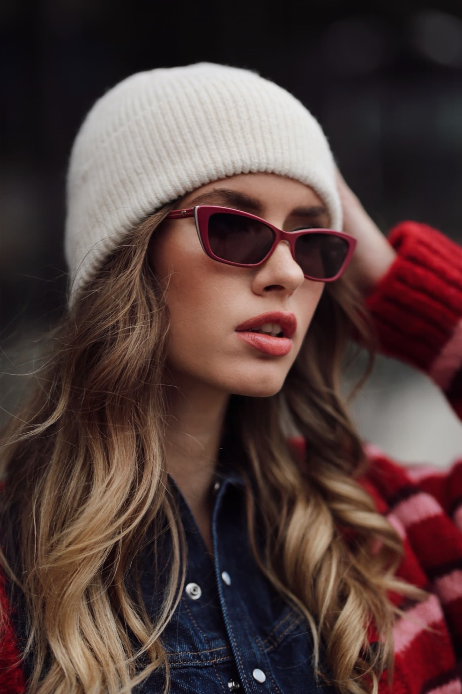Red-tinted sunglasses under a cream beanie
