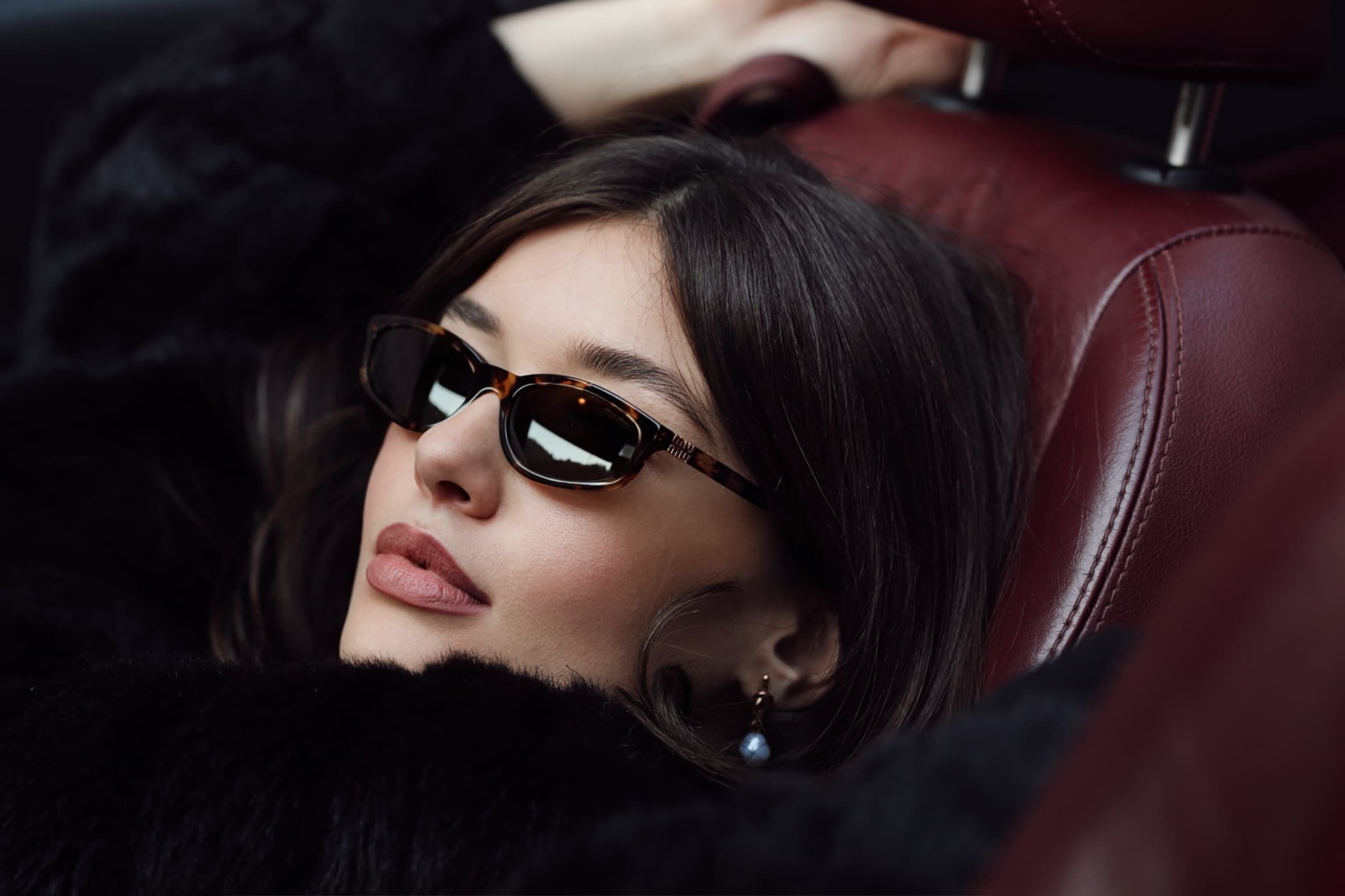Head back against the headrest, sunglasses catching the light