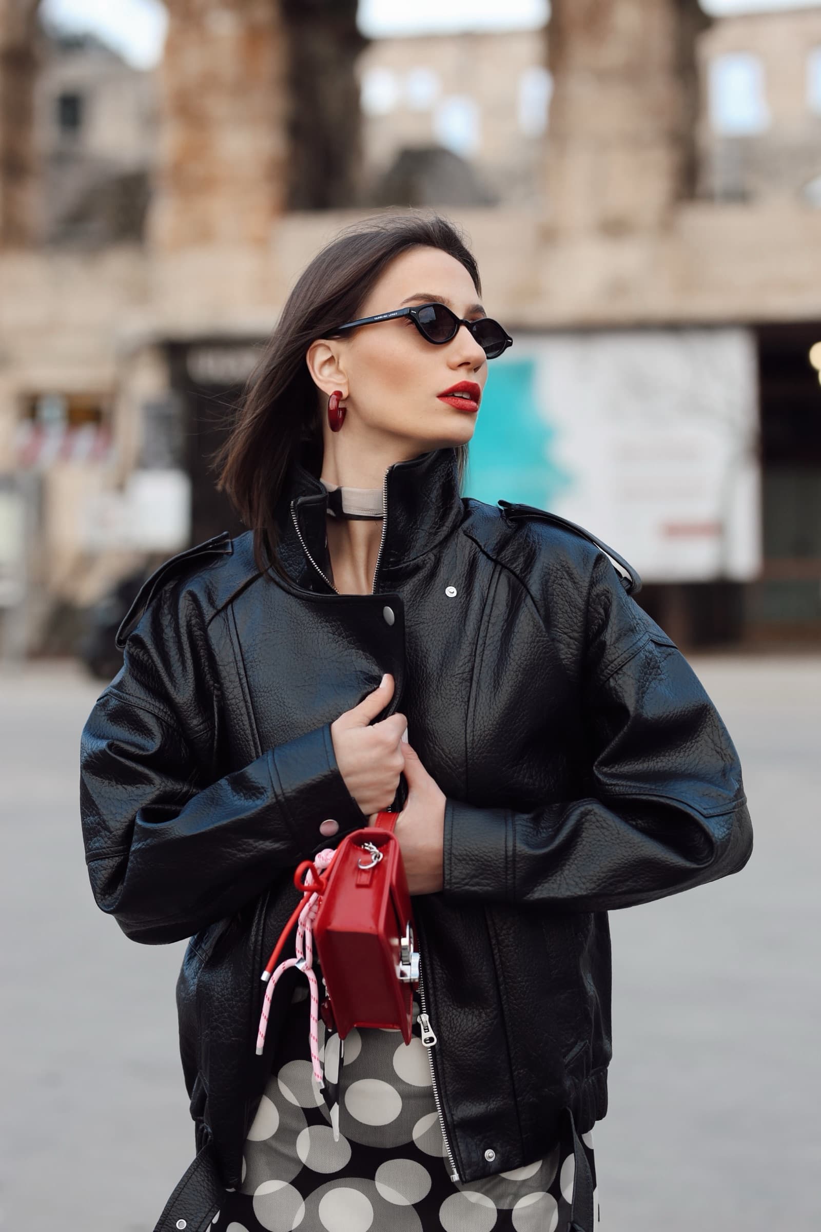 Red mini bag against the polka-dot skirt and leather bomber