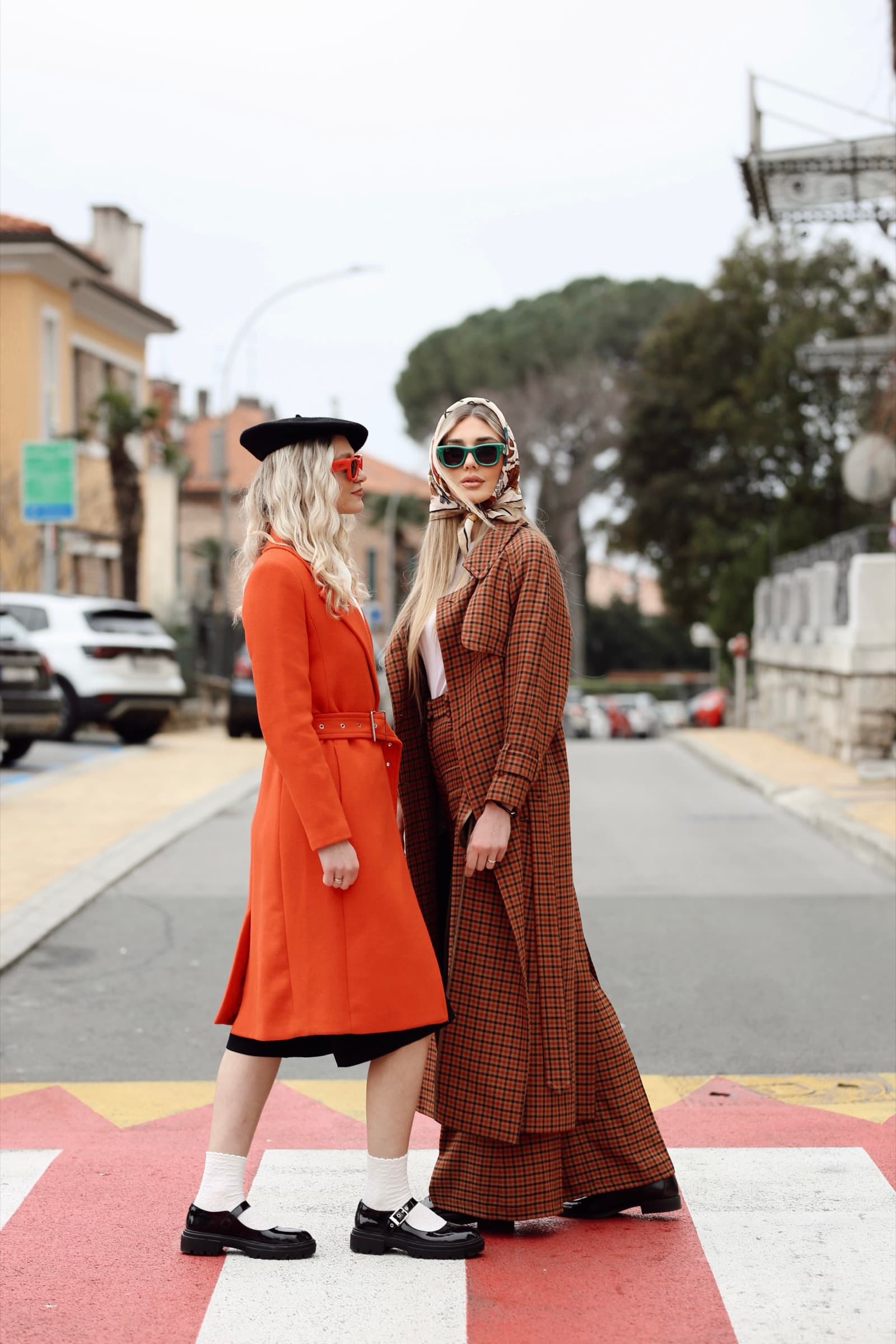 Two looks crossing the street, orange coat and brown check