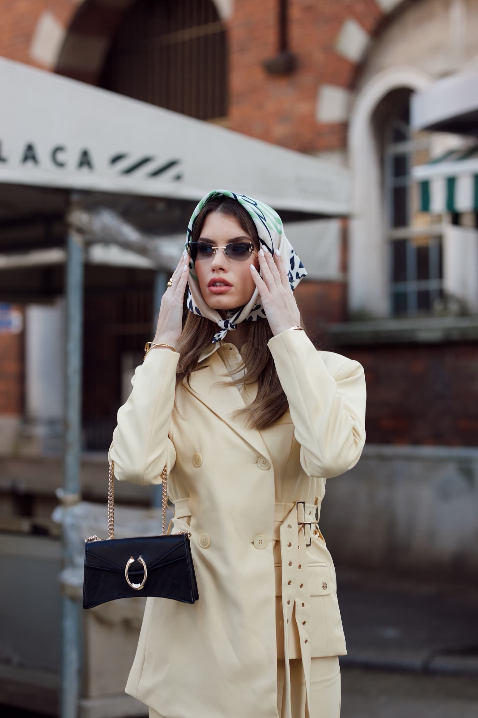 Cream coat and a black clutch under a striped awning