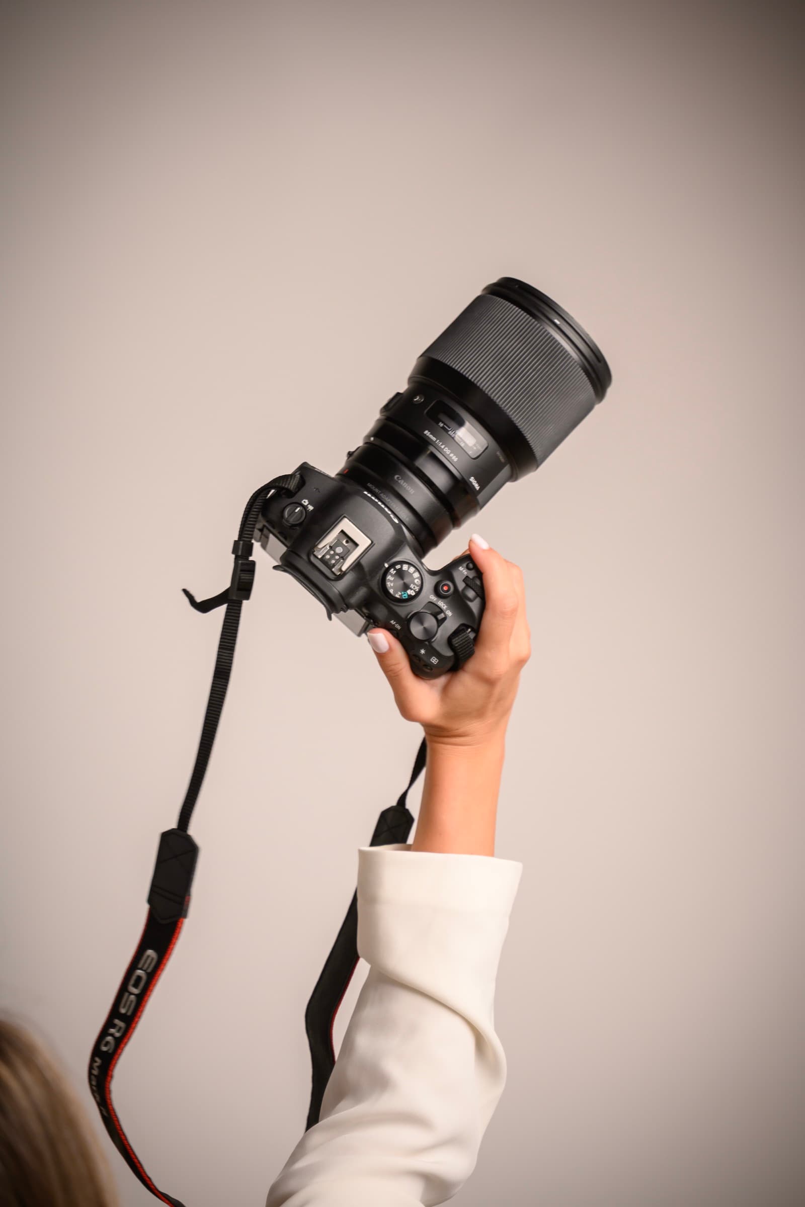 Maja holding her Canon R6 aloft against a warm greige backdrop
