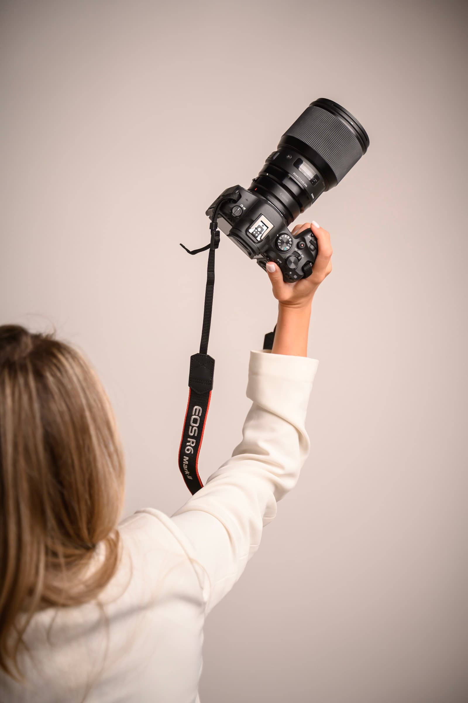 Maja photographed from behind, reaching up with her camera