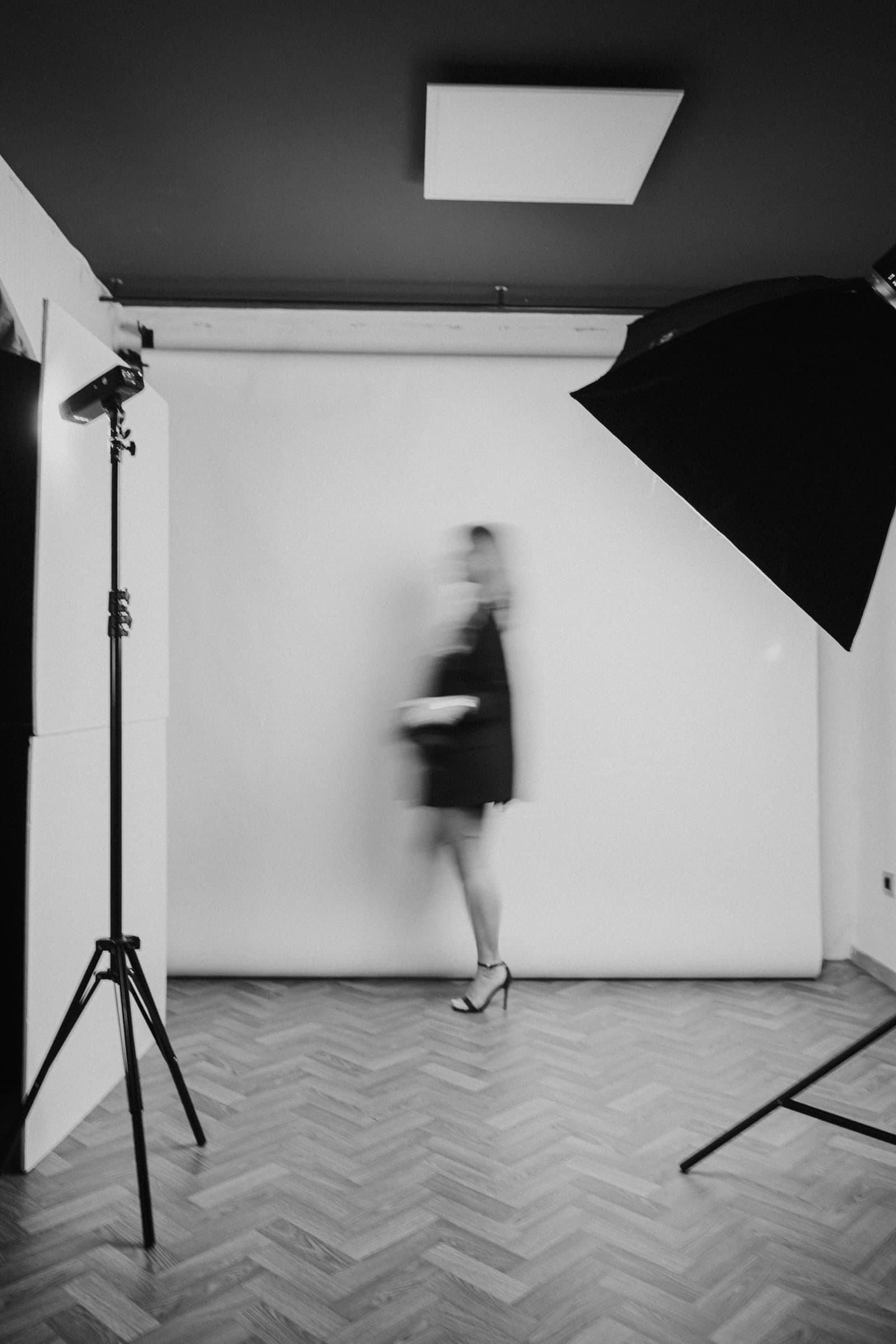 Maja's studio in black and white: seamless backdrop, softboxes, and a figure crossing the frame