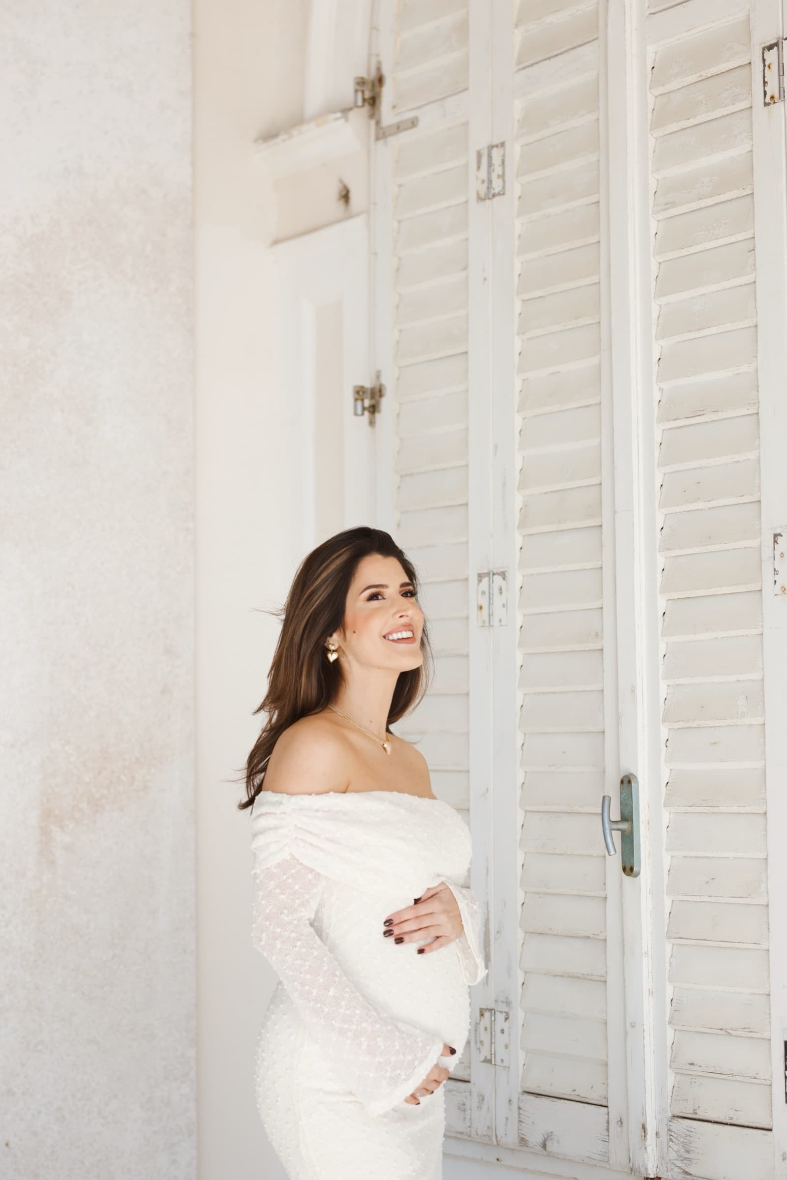 Standing away from the shutters, smiling into the light