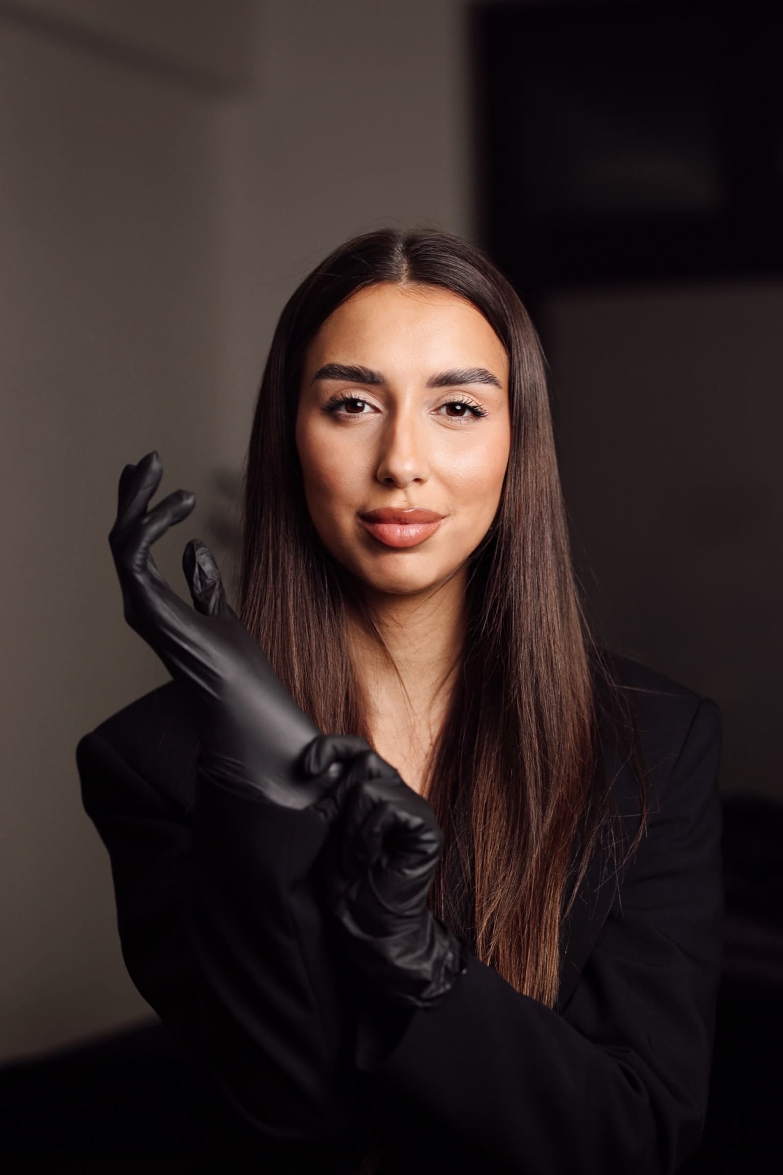 Studio portrait with long black gloves against deep shadow
