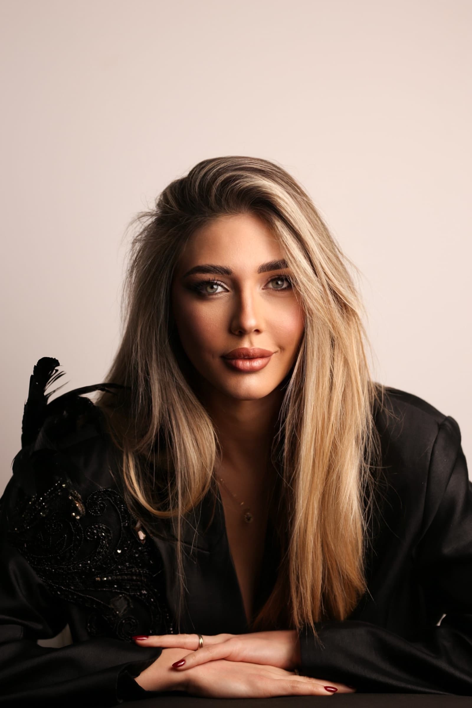 Studio portrait against blush, black sequinned sleeve