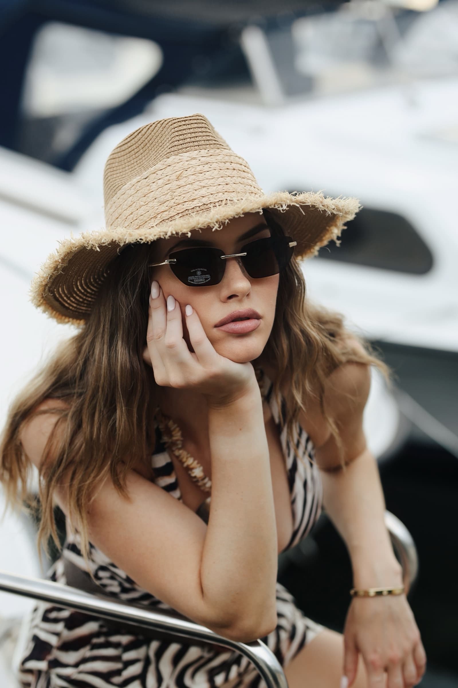 Zebra-print swimsuit and straw hat, resting against the yacht rail