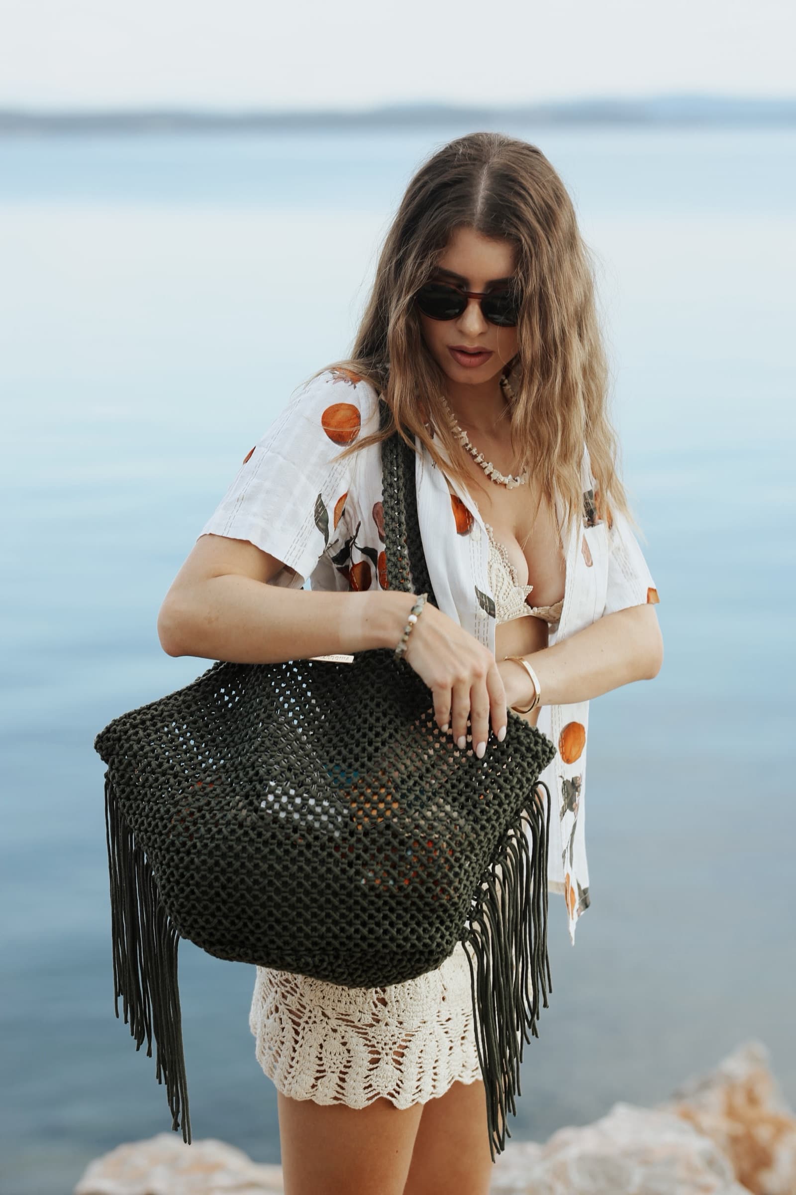 Fringed net bag and a fruit-print shirt by the sea