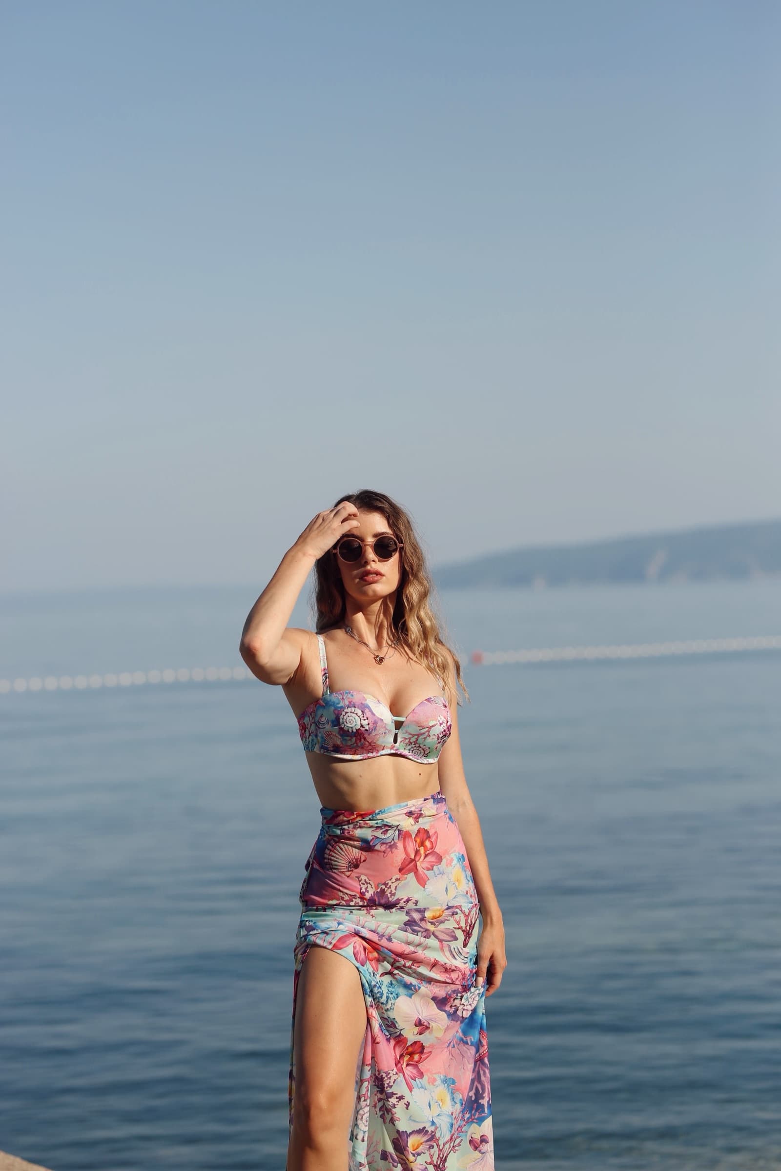 Floral sarong and bikini, hand shading the eyes