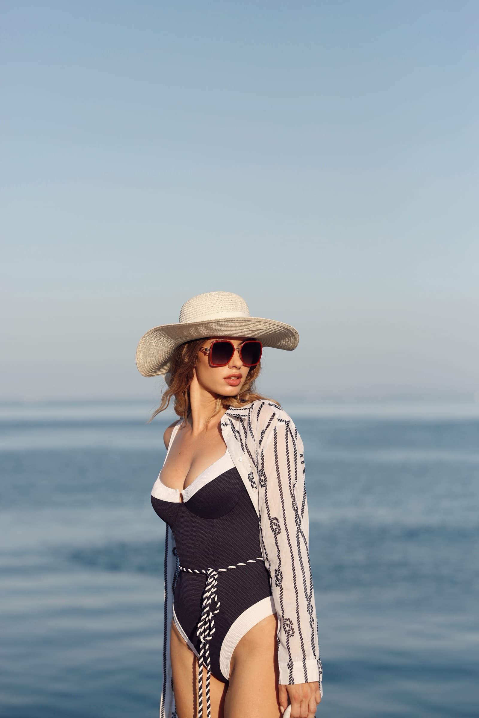 Wide-brim hat and a lace-up swimsuit against flat calm water