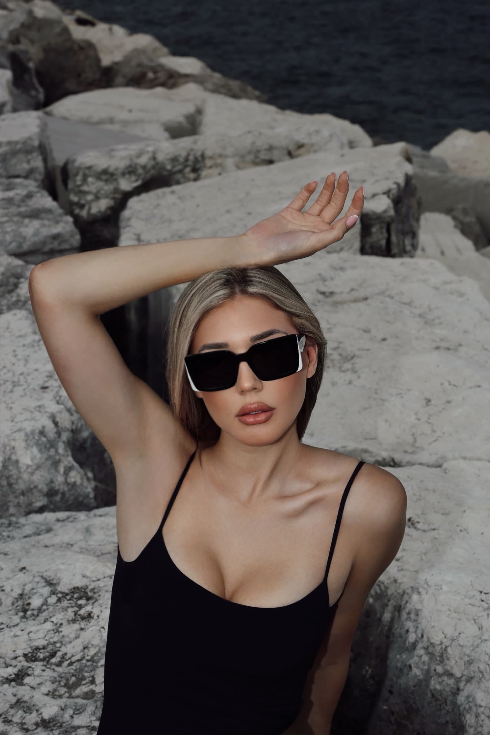 Black swimsuit against pale rock, arm raised to the light