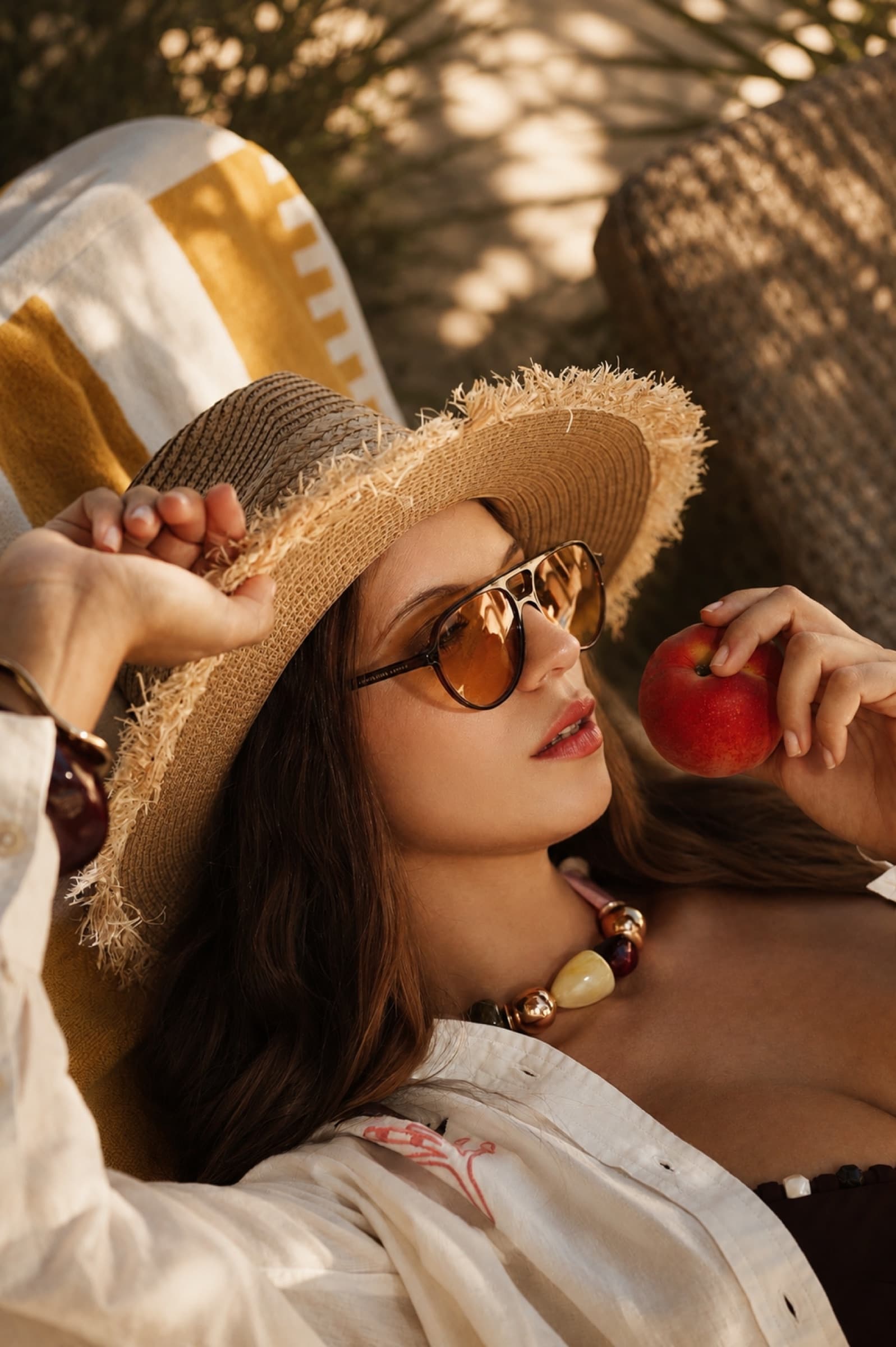 Reclining in a straw hat with a peach in hand